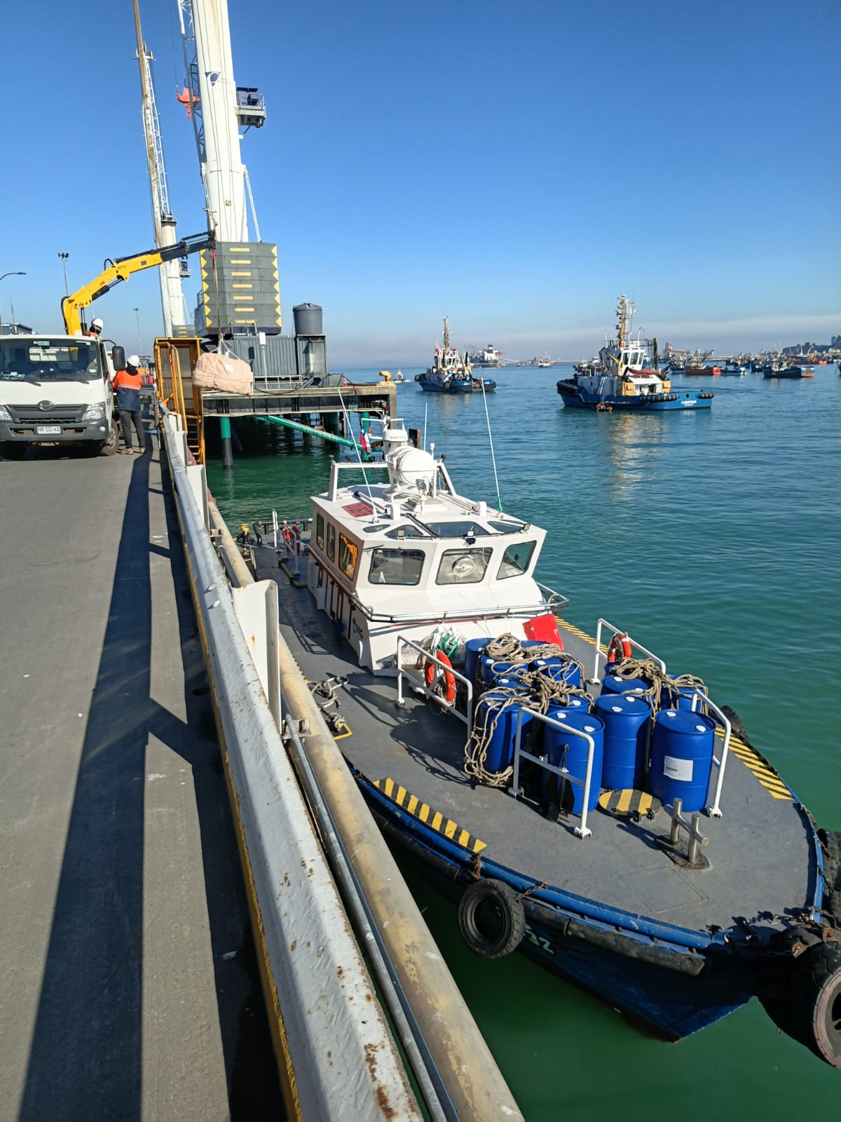 Supply launch loaded with chemical drums at port
